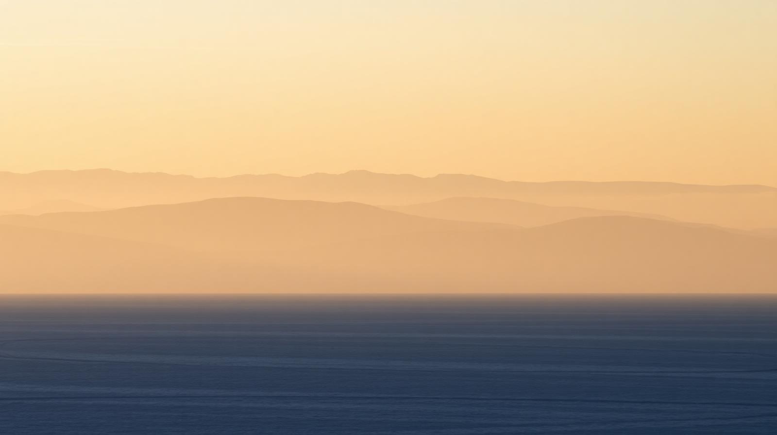 A serene open landscape bathed in soft golden morning light, evoking a sense of stillness, spaciousness, and inner freedom.